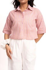 A woman wearing a pink and white vertically striped short-sleeve button-up shirt tucked into white pants, shown from the neck down against a plain white background.