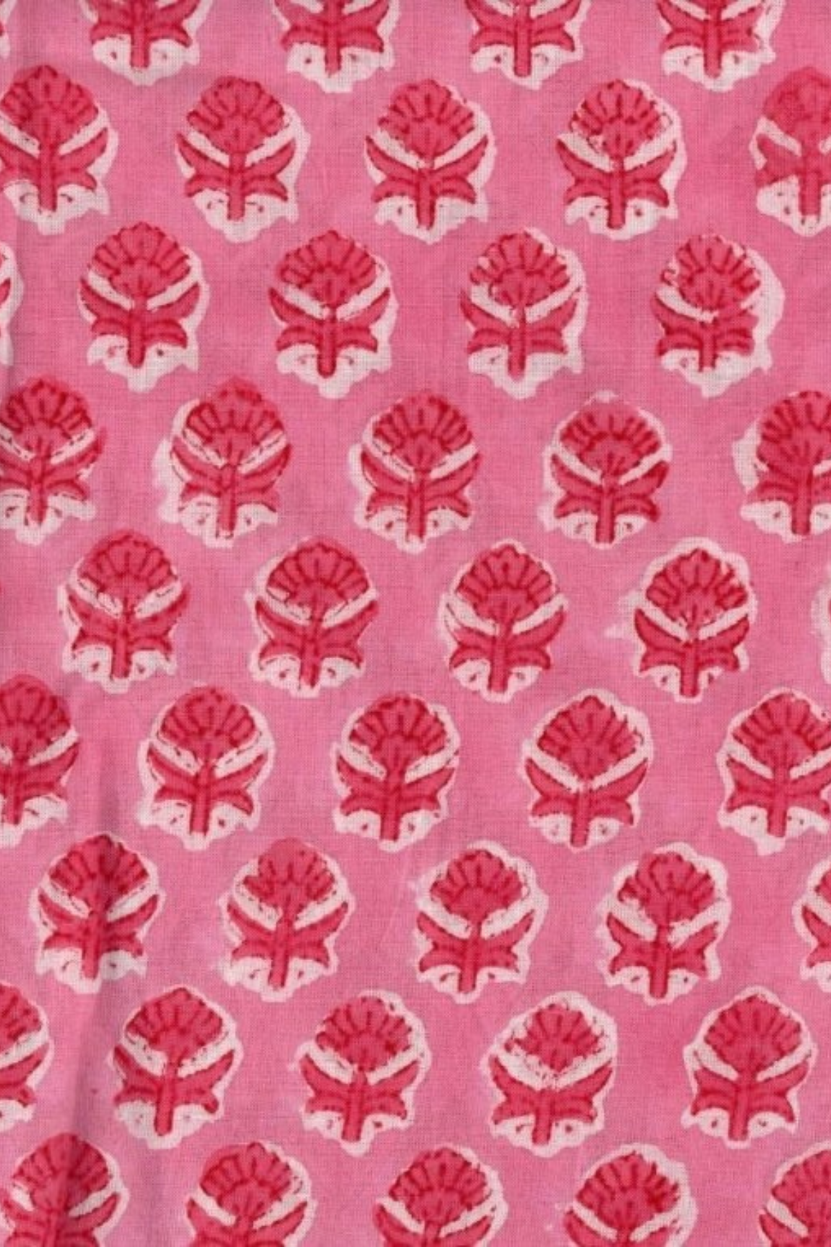 Pink fabric with a repeating red and white block-printed floral pattern.