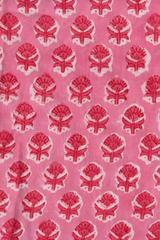 Pink fabric with a repeating red and white block-printed floral pattern.