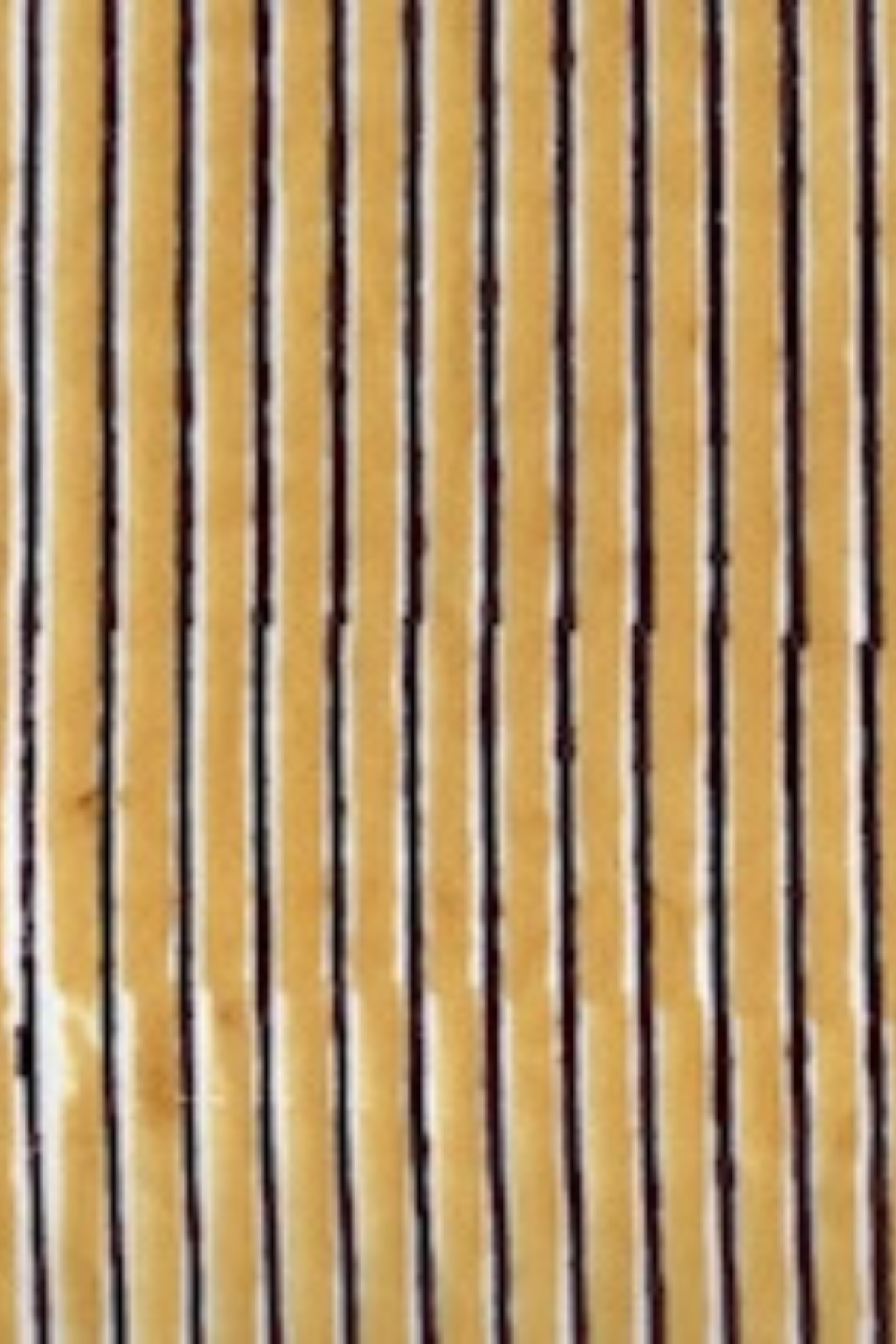 A close-up of a striped fabric or material with alternating vertical tan/beige and dark brown stripes.