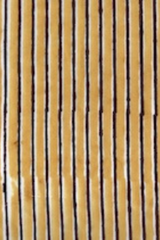 A close-up of a striped fabric or material with alternating vertical tan/beige and dark brown stripes.